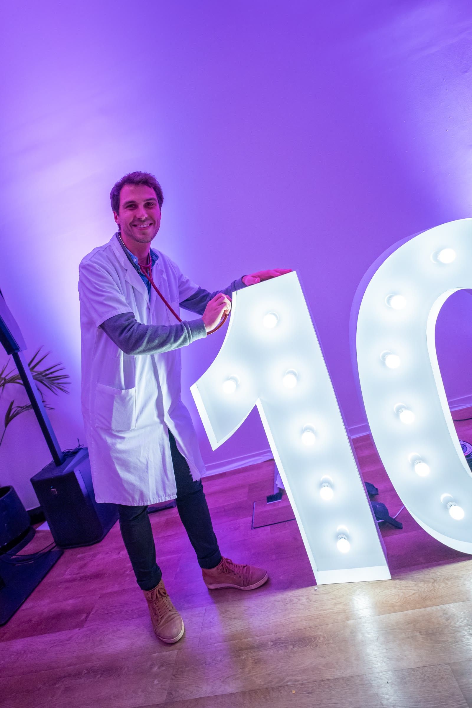 Invité en blouse blanche devant le grand « 10 » lumineux