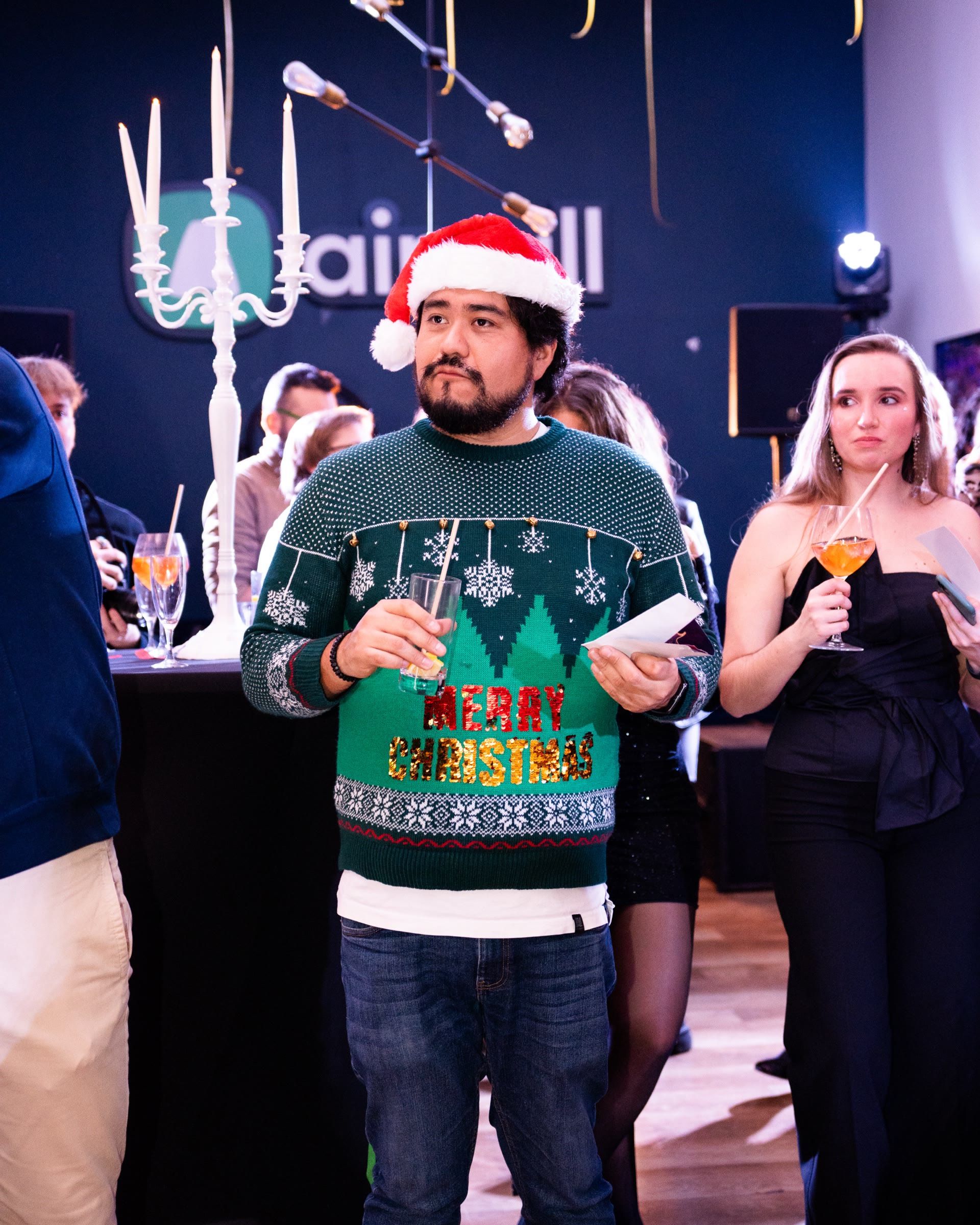 Invité en pull de Noël et bonnet de père Noël devant le logo Aircall