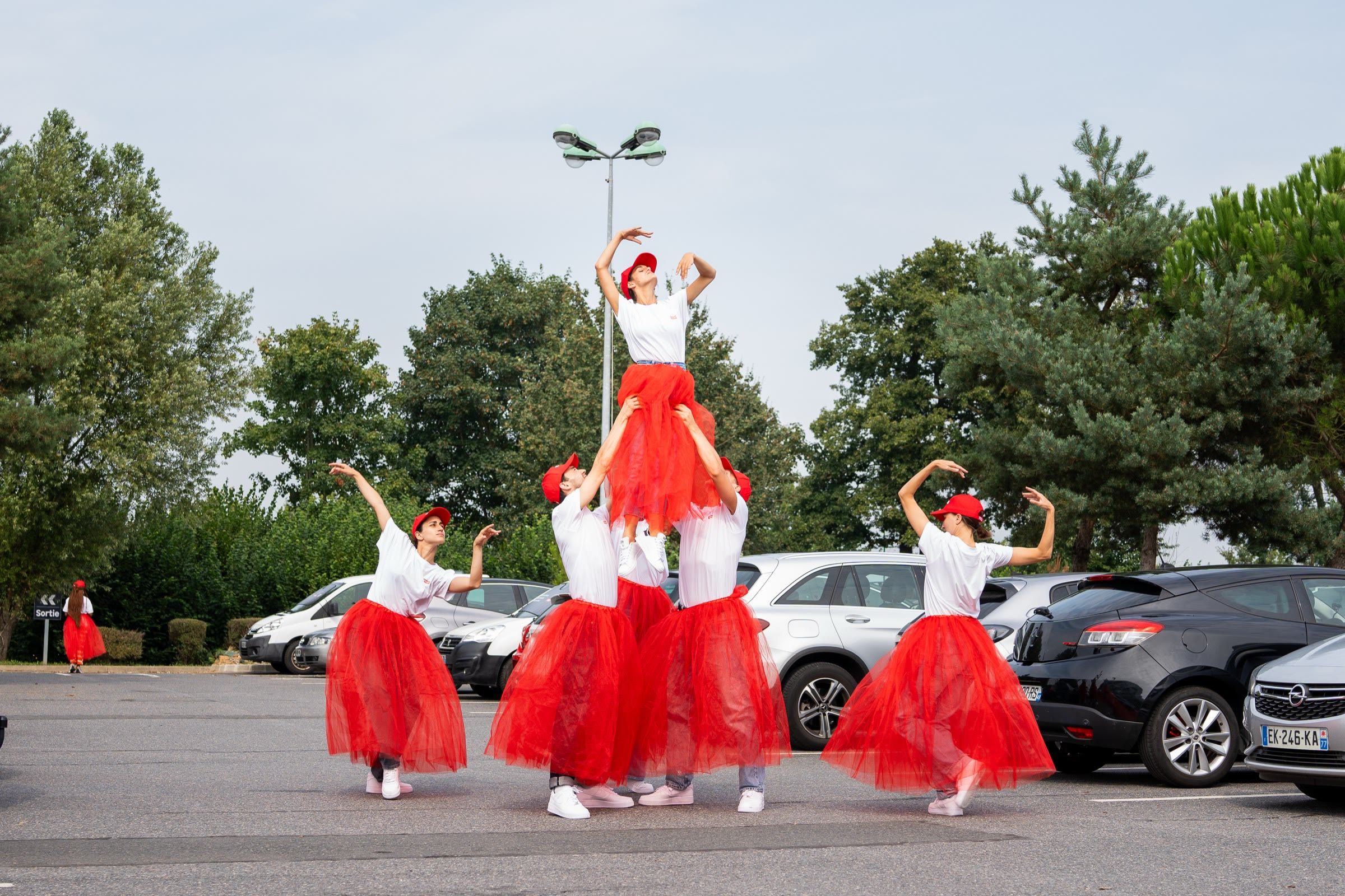 Danseuses en jupes de tulle rouge formant une pyramide sur le parking