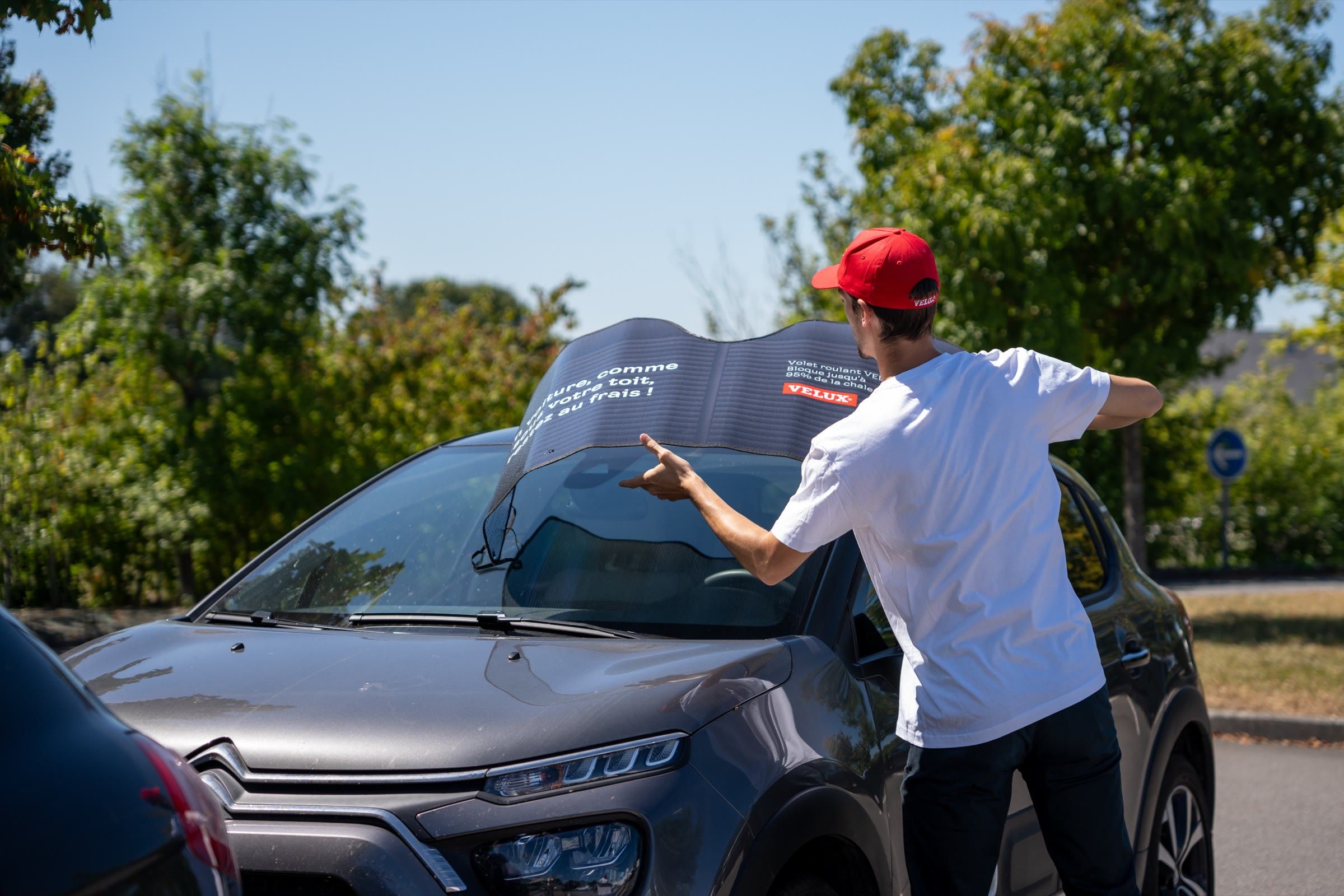 Un ambassadeur déplie un pare-soleil Velux sur une voiture